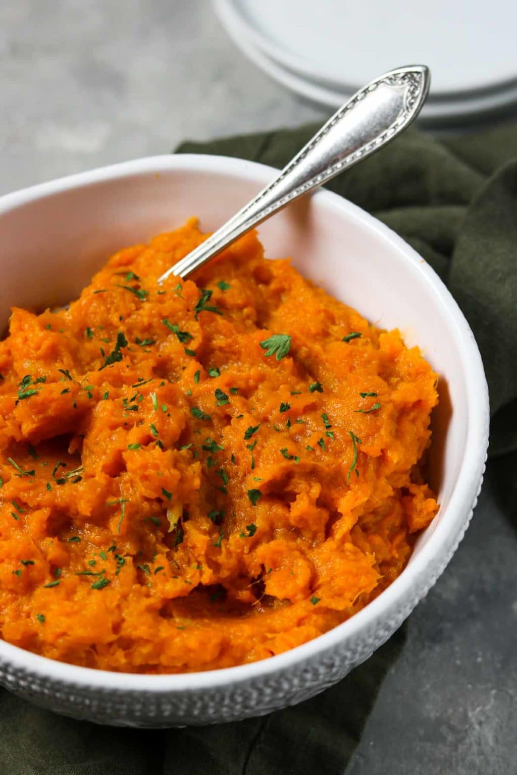 Savory Mashed sweet potatoes in a white bowl with a spoon