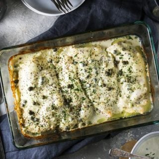 creamy caesar chicken in a baking dish with lemon to the side