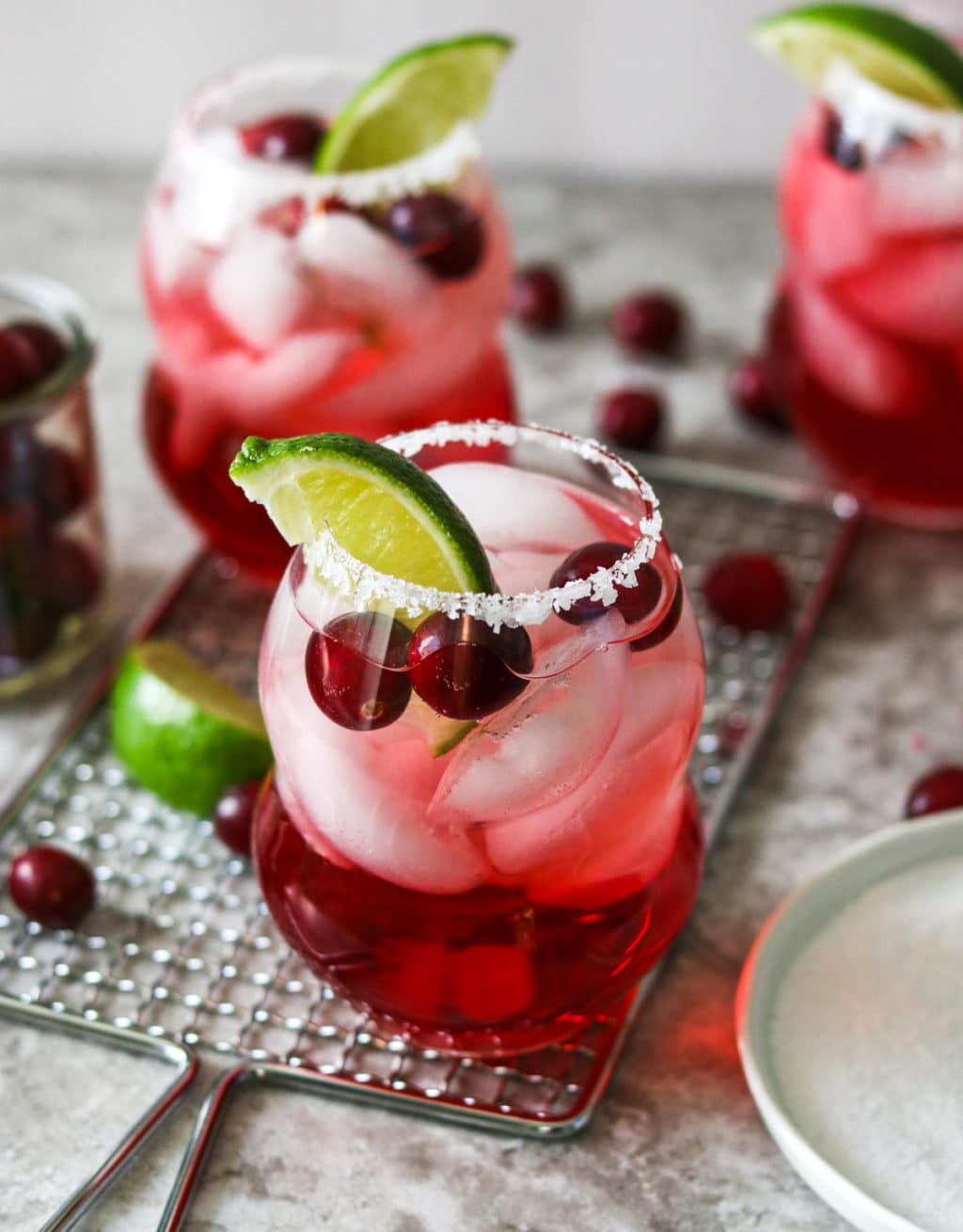 three cranberry ginger margaritas garnished with fresh cranberries and limes
