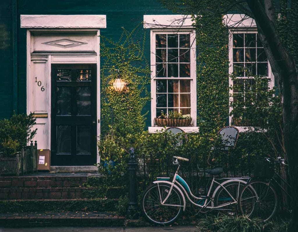 blue house with a black and white door and a blue bike leaning on a fence