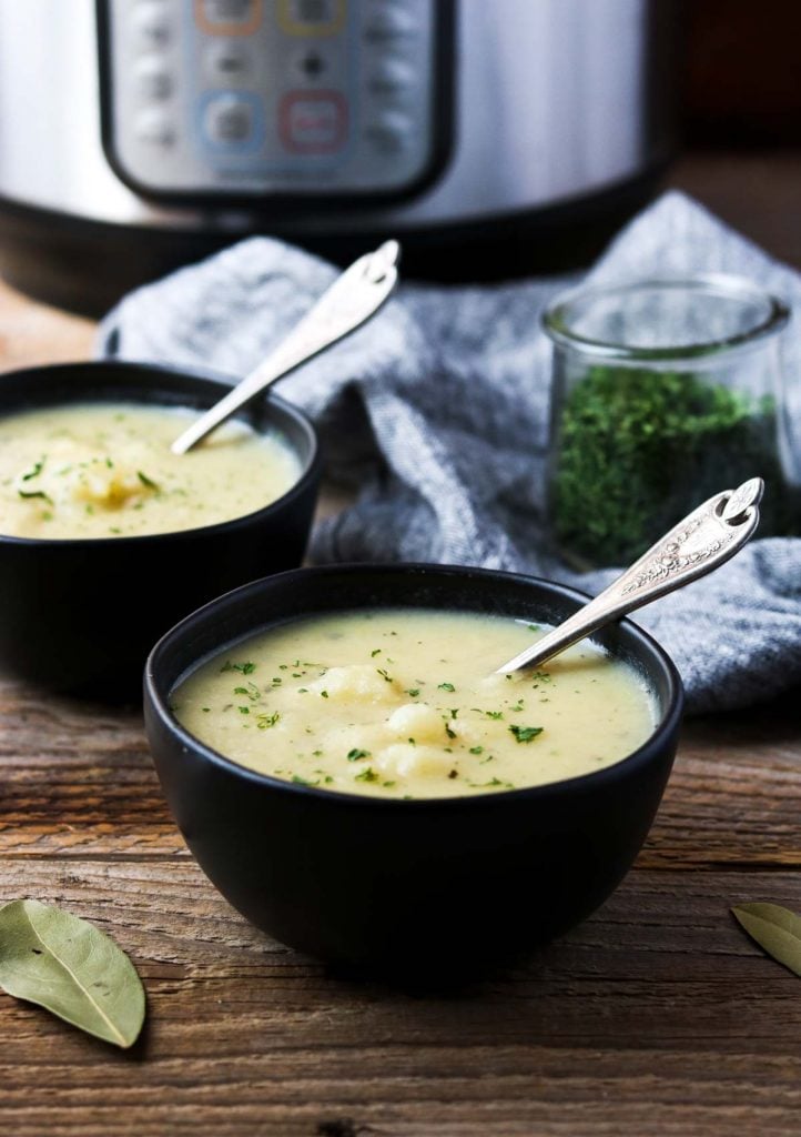 two bowls full of potato soup with two spoons