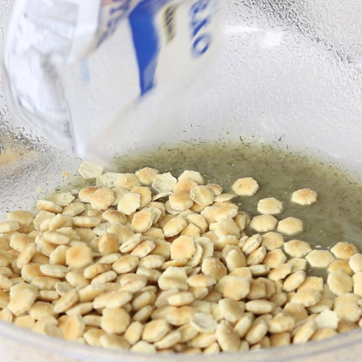 Oyster crackers being poured into a seasoning mixture