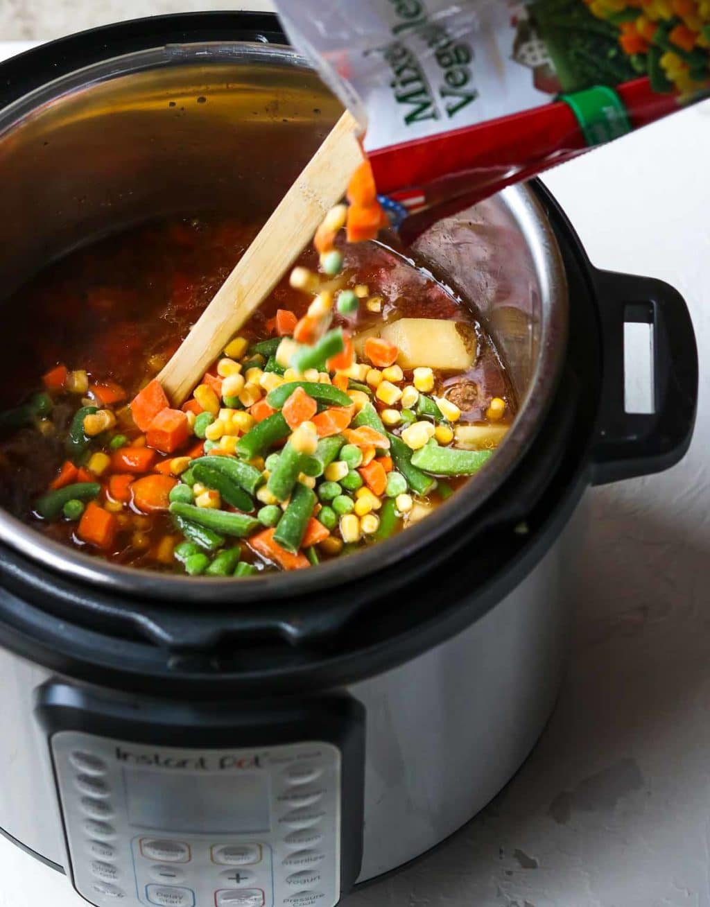 Frozen Mixed Vegetables being poured into the instant pot 