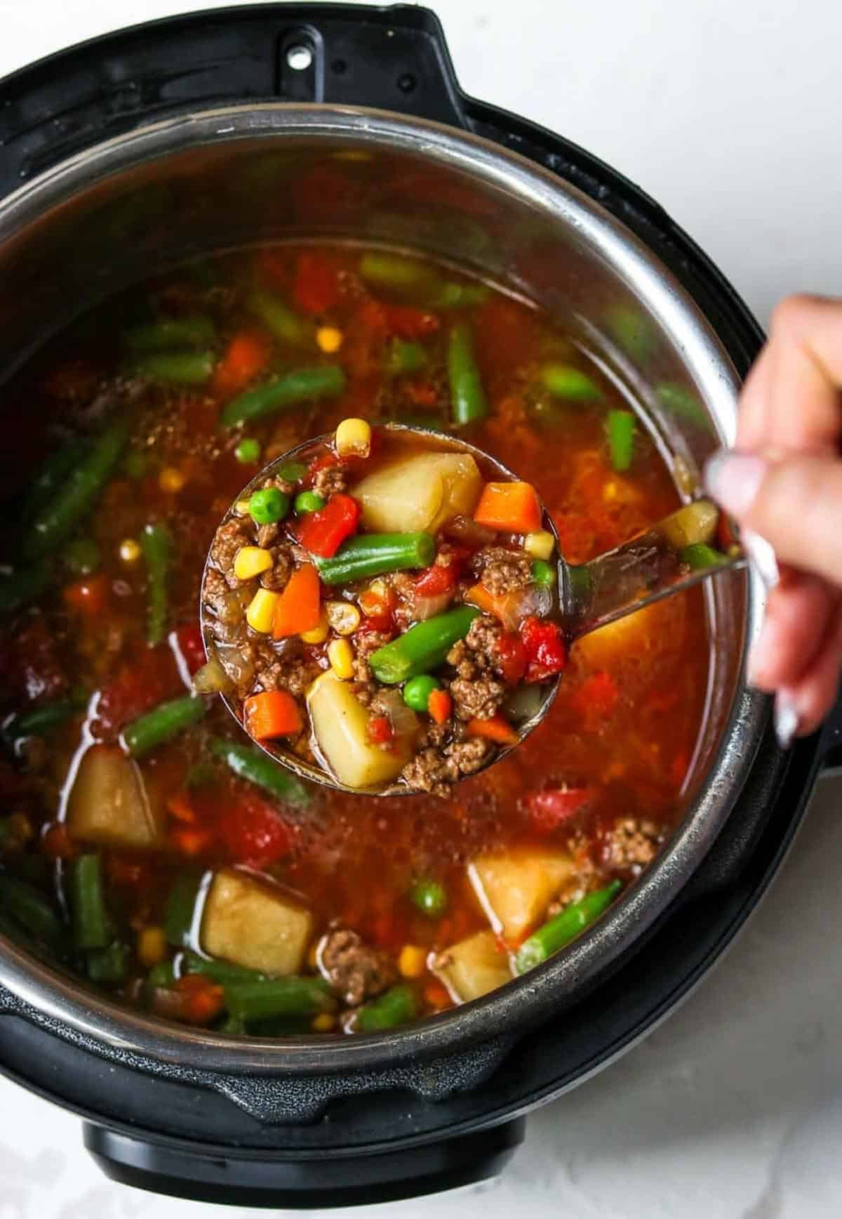 a ladle full of hamburger soup over the instant pot