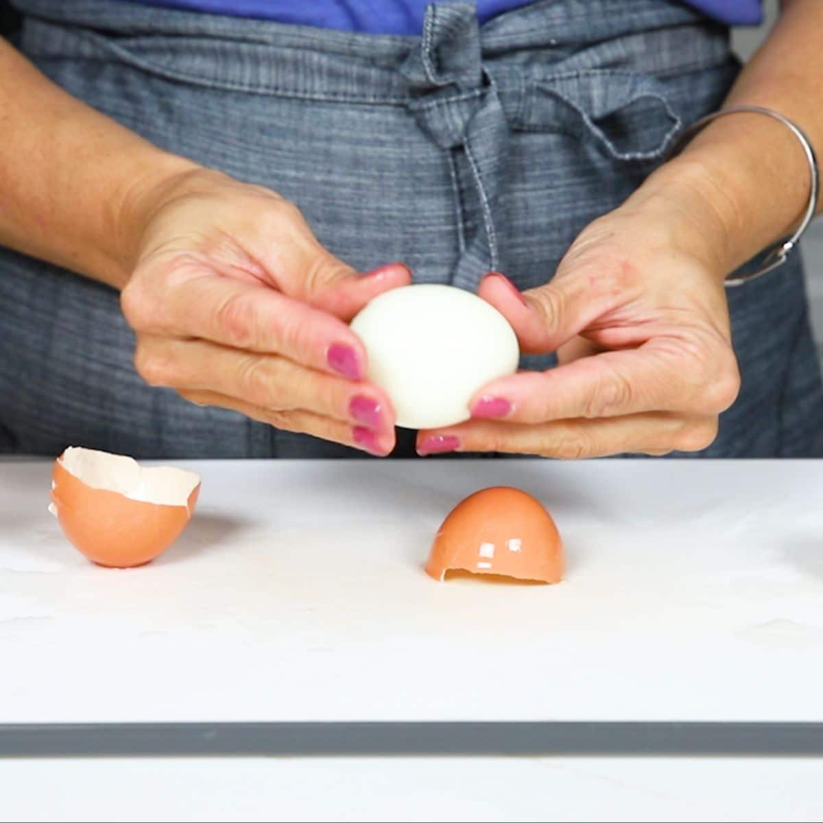 a hard boiled egg peeled open with two shell pieces on the table 