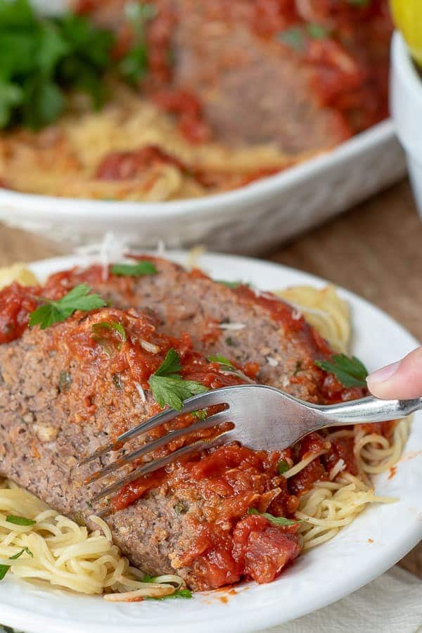 Italian Meatloaf over spaghettti on a white plate