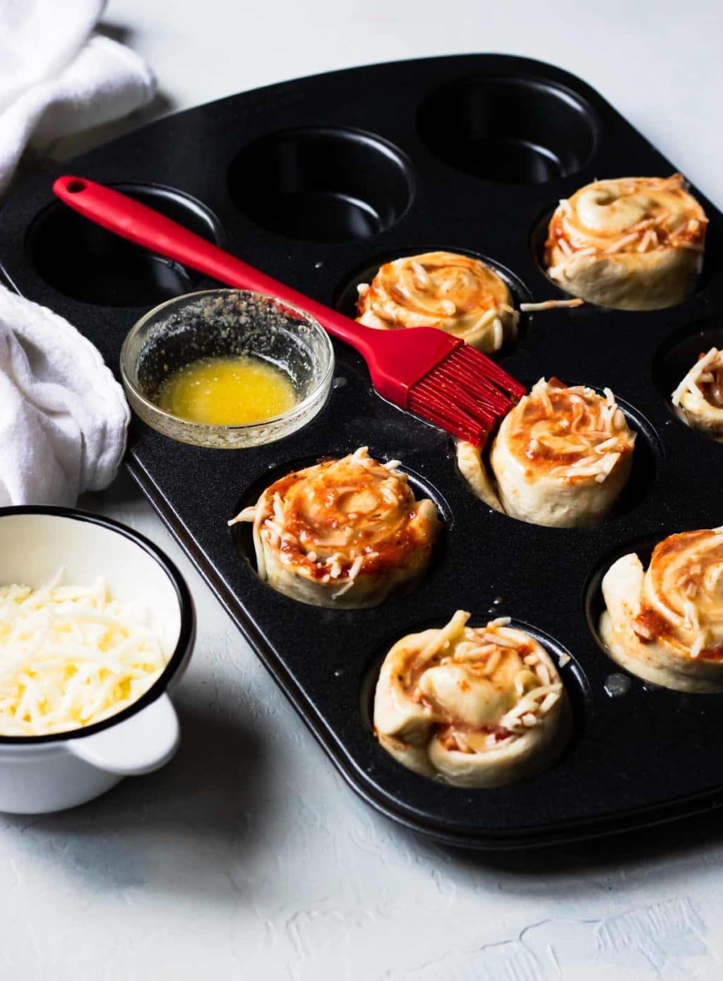 Pizza Roll Ups in a cupcake pan, topped with garlic butter