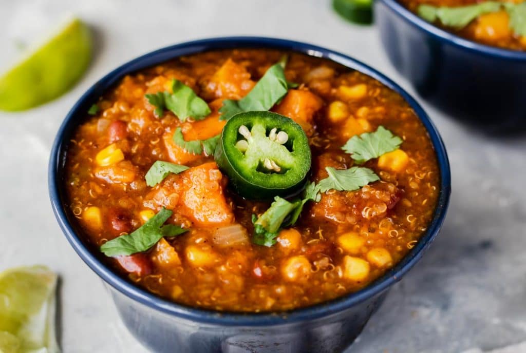 A bowl of quinoa sweet potato chili garnished with a jalapeno and cilantro 