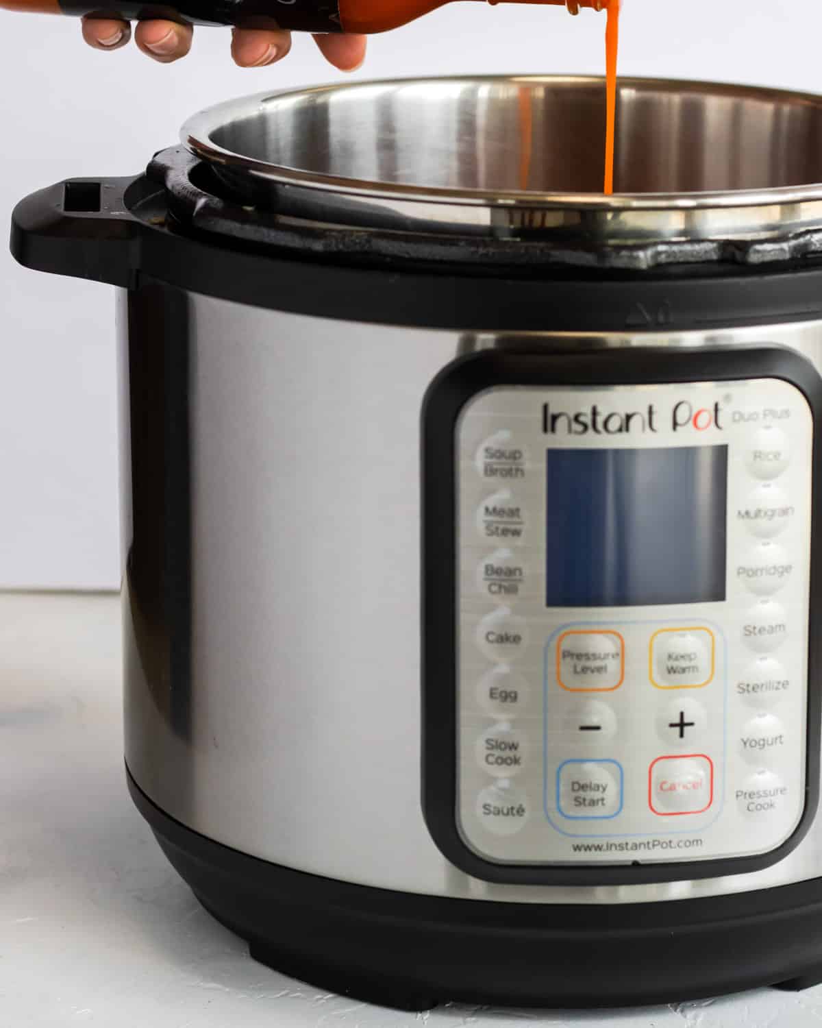 instant pot with buffalo sauce being poured in