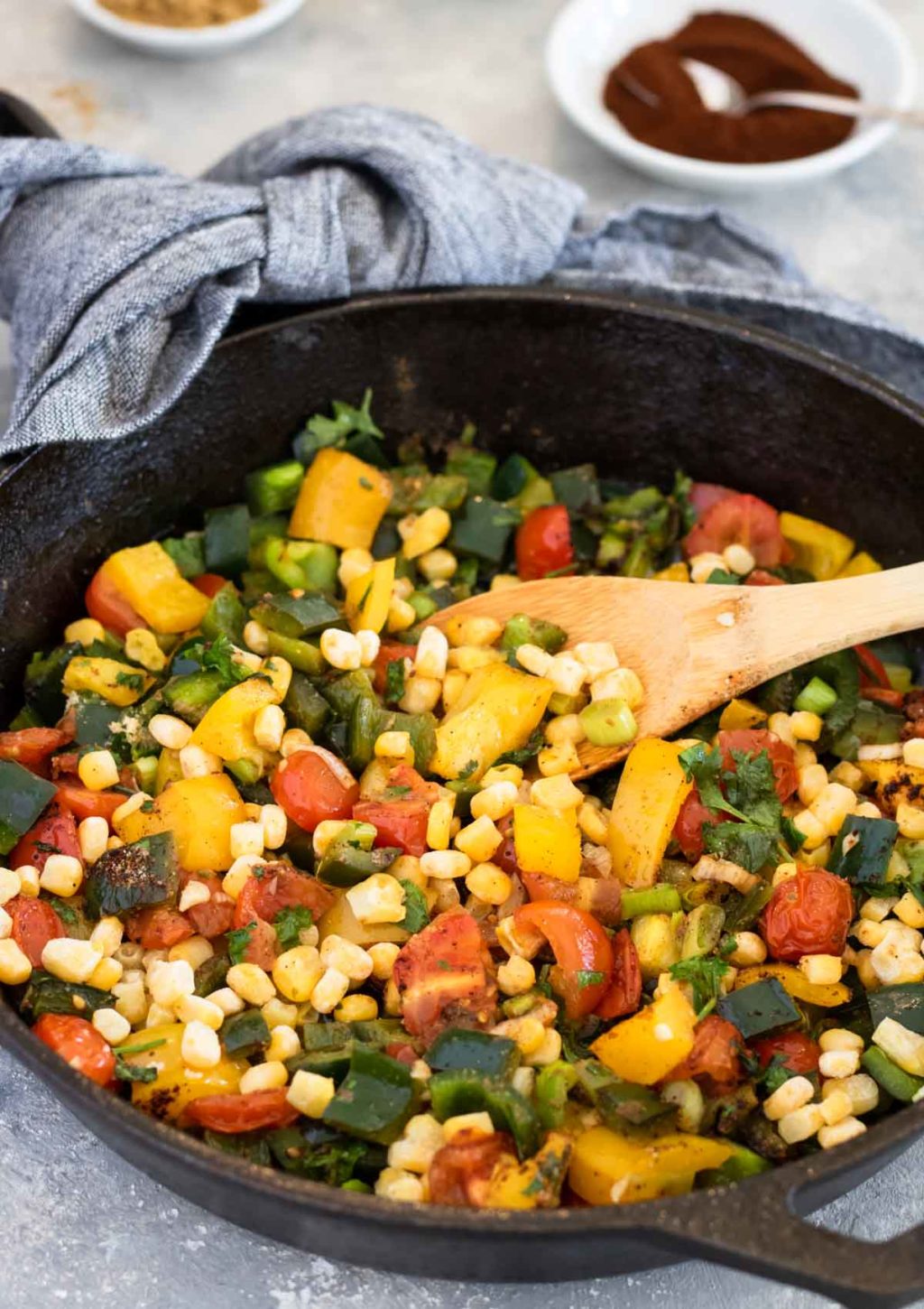 poblano peppers, tomatoes, corn, green onions, cilantro, bell peppers in a cast iron skillet
