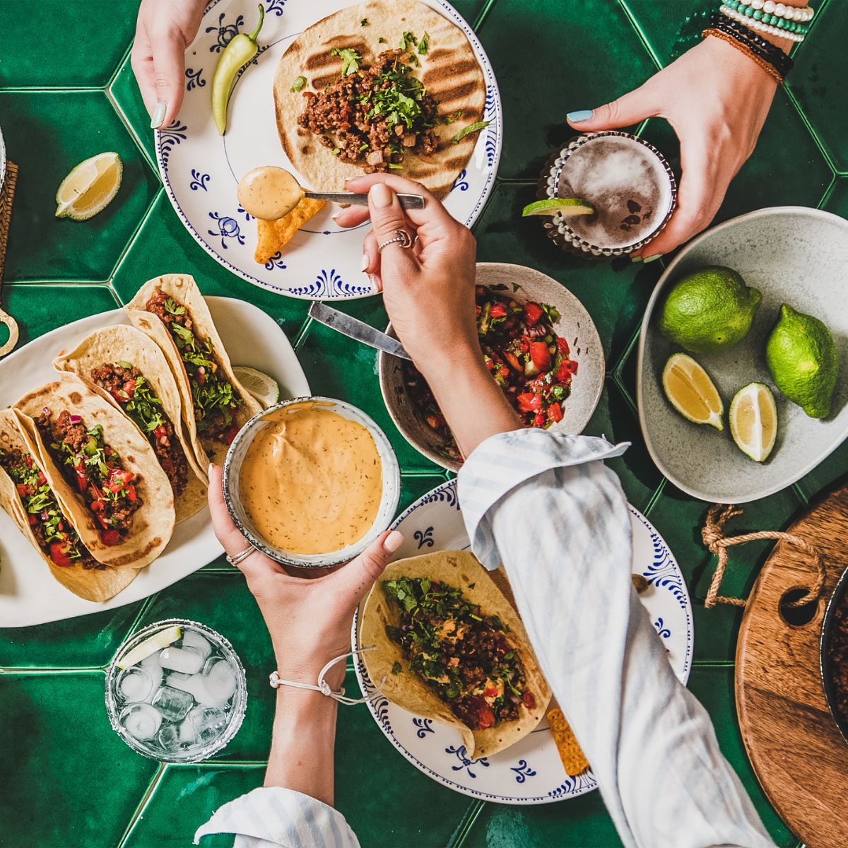 A taco dinner party table from above, hands reaching over the table