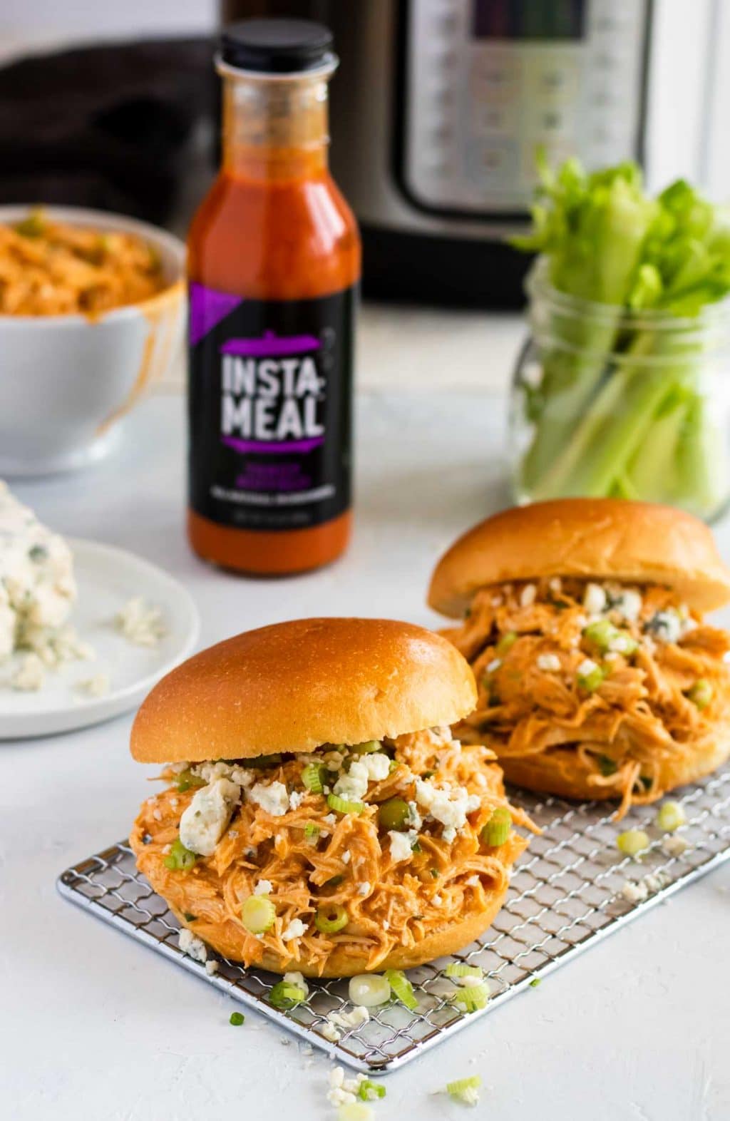 two buffalo chicken sandwiches with insta-meal buffalo sauce and an instant pot in the background