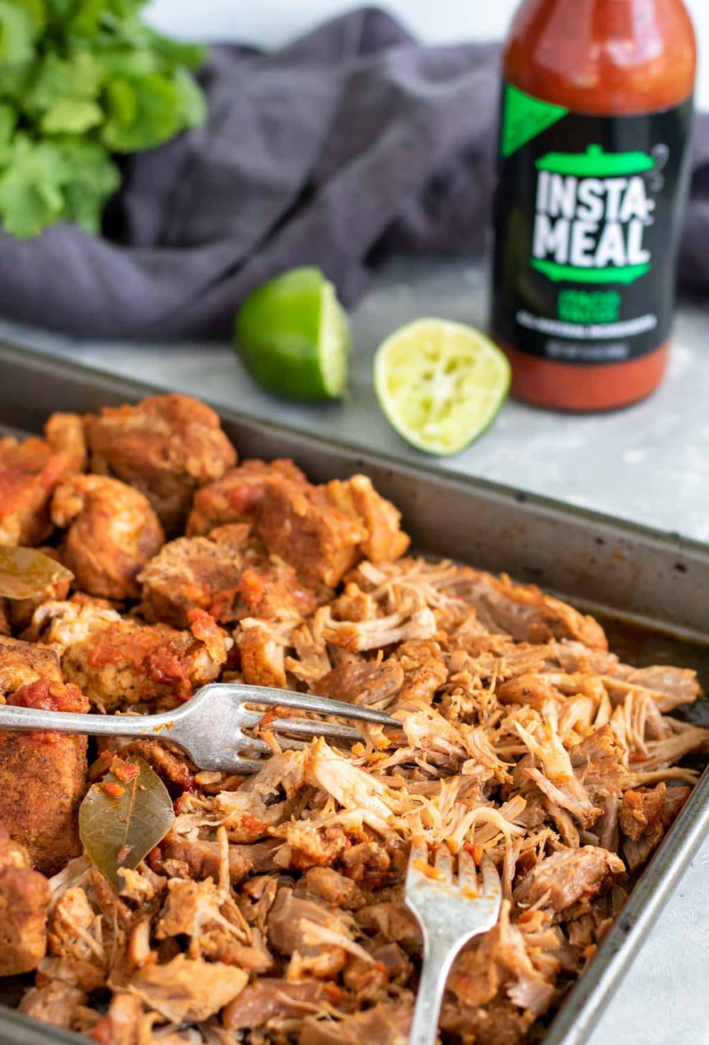 Instant Pot Carnitas on a rimmed baking sheet shredded with two forks