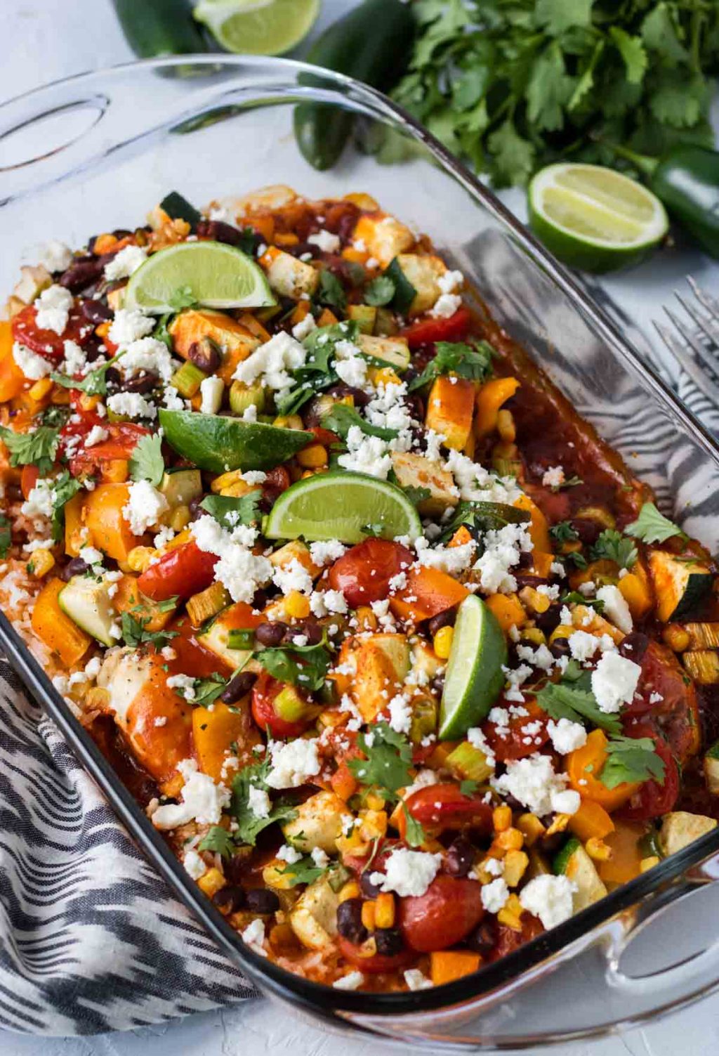 Healthy Mexican Casserole in a glass baking dish topped with queso fresco and limes