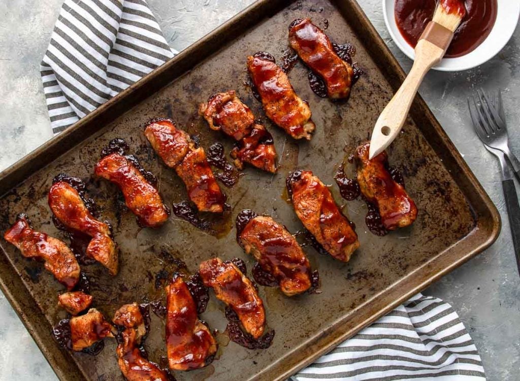 country style boneless pork ribs coated with bbq sauce on a sheet pan