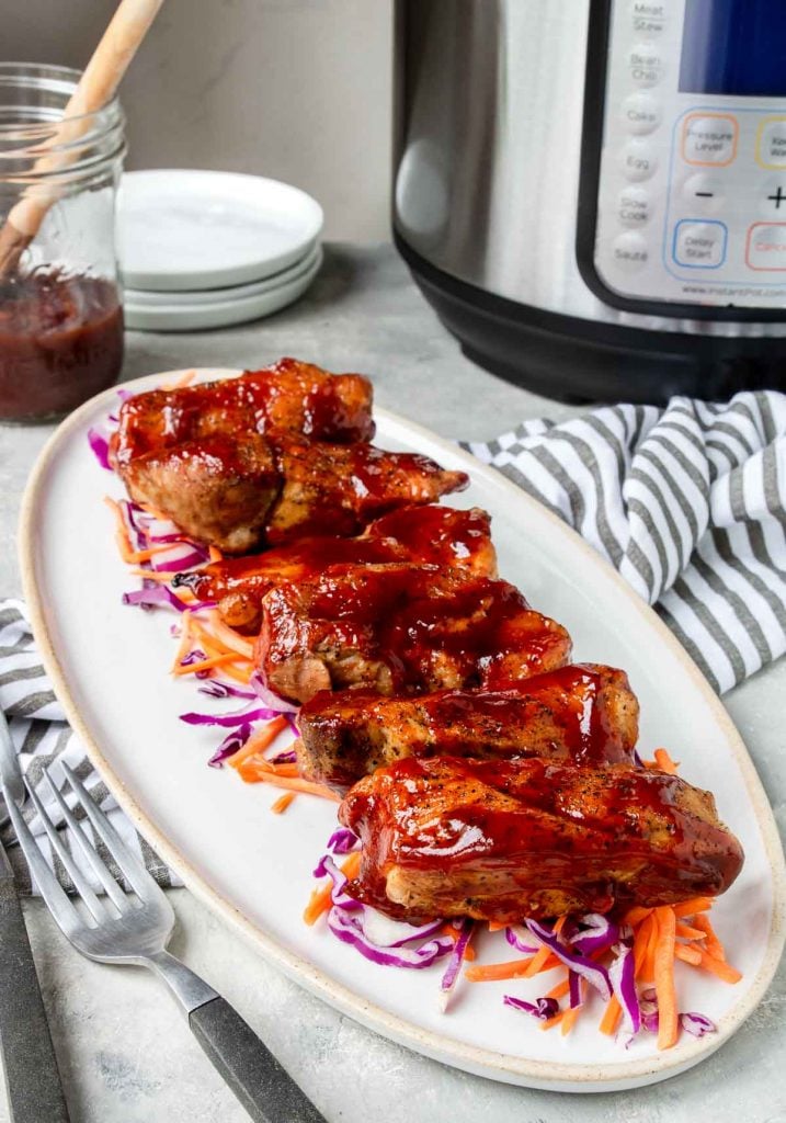 Instant Pot Boneless Pork Ribs on a white plate with an electric pressure cooker in the background