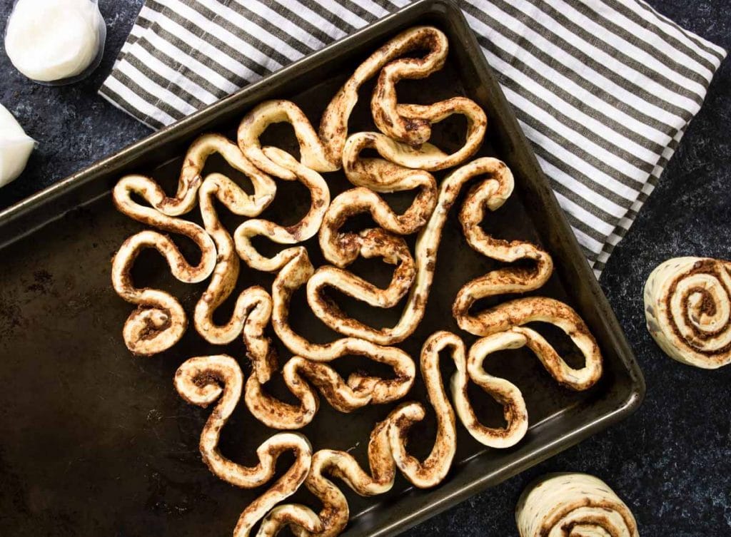 Cinnamon rolls strips coiled and twisted on a baking sheet - looks like intestines