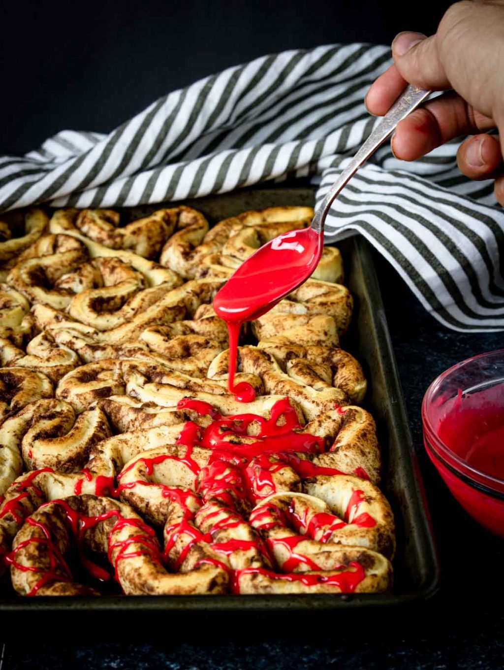 Drizzling red frosting on the bloody guts cinnamon rolls for a Halloween Breakfast