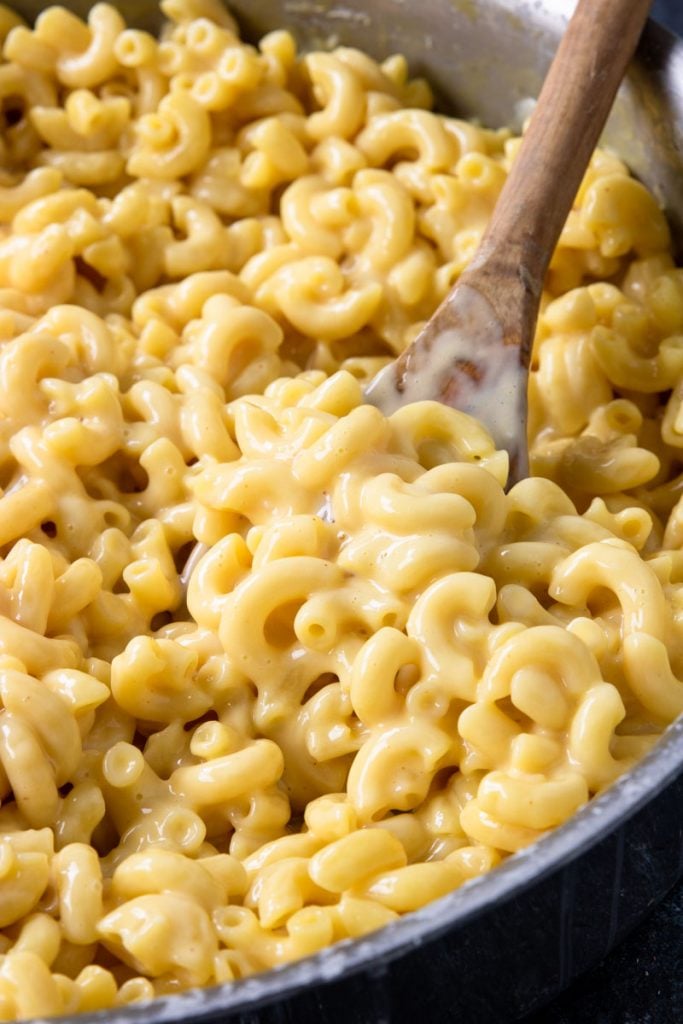 Skillet Mac and Cheese looking creamy and cheesy on a wooden spoon