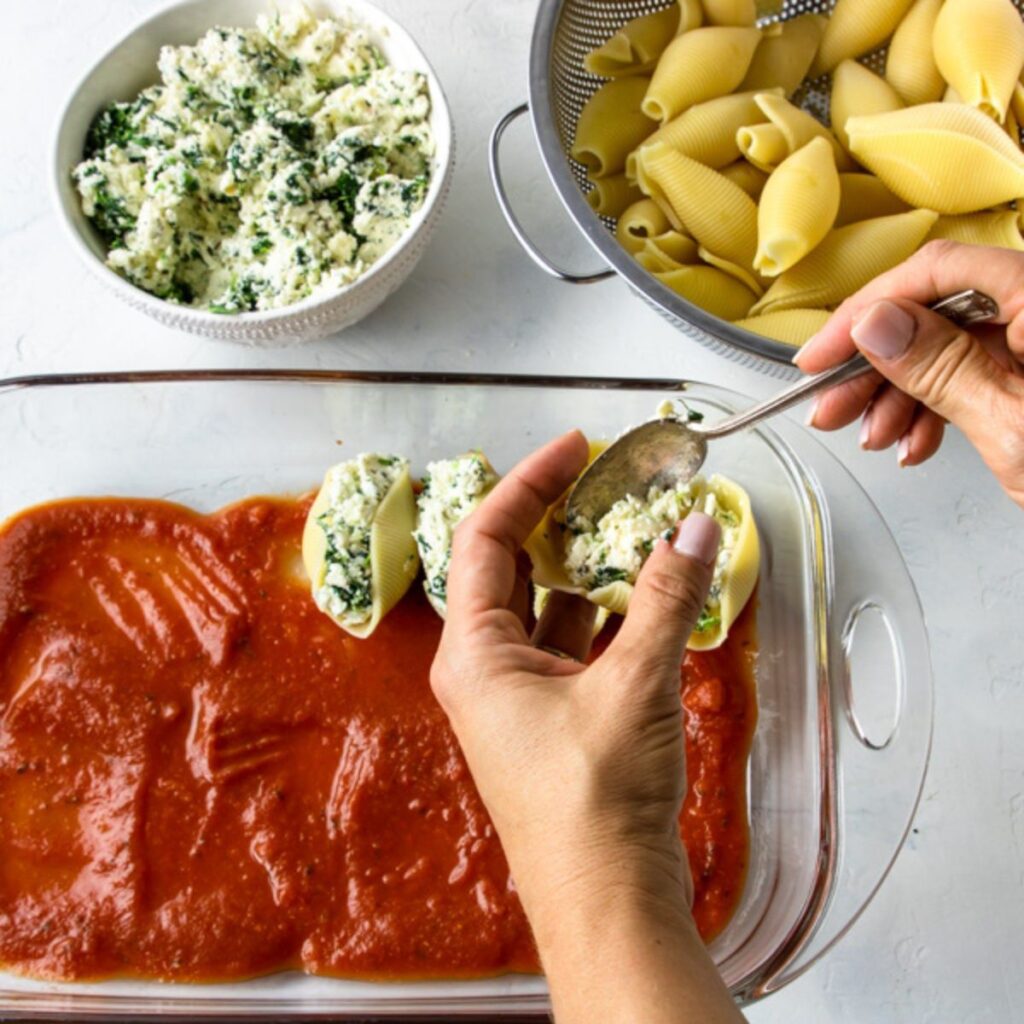 stuffing shells and placing in a prepared 9x13 baking pan with marinara sauce on the bottom