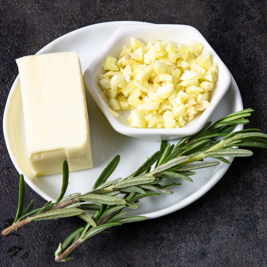 a small plate with butter, garlic and rosemary