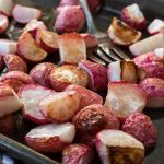 radishes roasted on a baking sheet with a fork