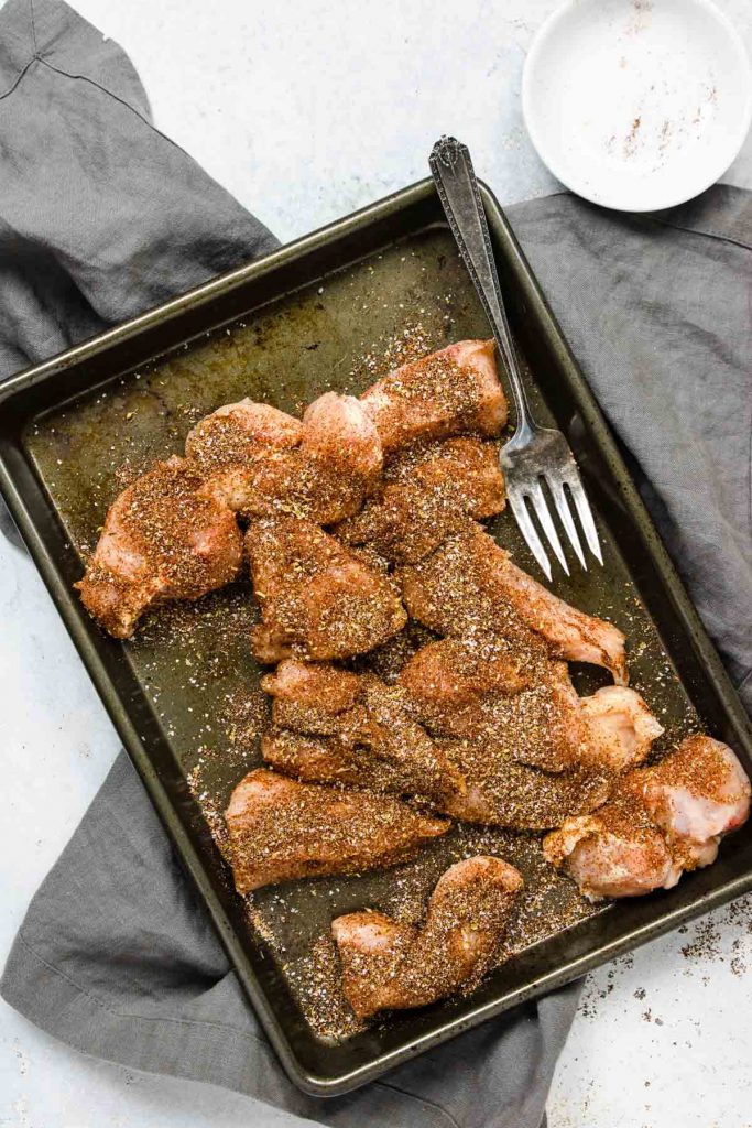 Chicken pieces seasoned on all sides with the taco seasoning. sitting on a baking sheet
