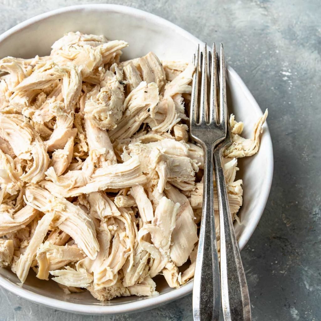 Shredded Rotisserie Chicken in a white bowl with two forks