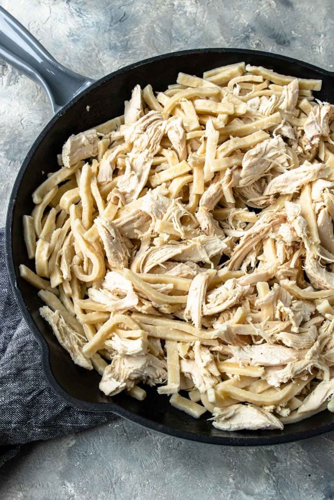 Homestyle egg noodles and shredded chicken mixed together in a large skillet