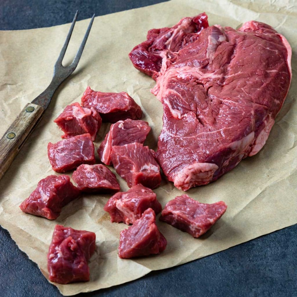 Top Sirloin Steak on butcher paper, cut into 1 inch chunks