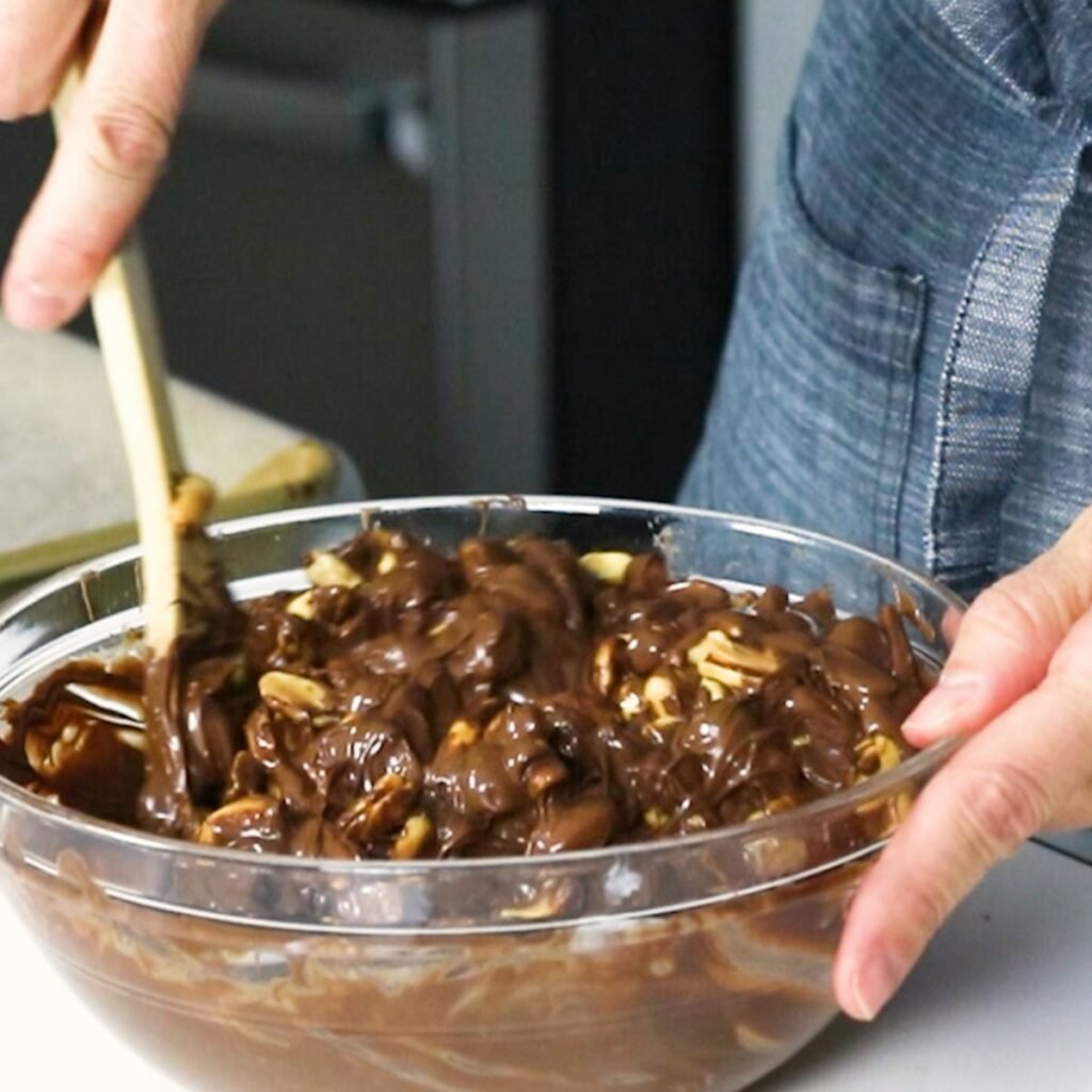 Stirring cocktail peanuts into melted chocolates 