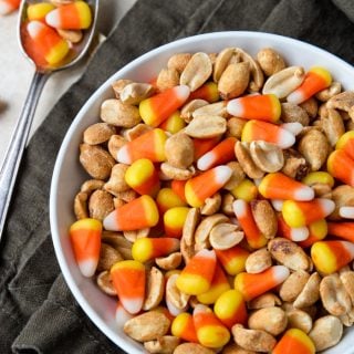 Candy Corn and peanuts mixed in a bowl with a few spilled to the side