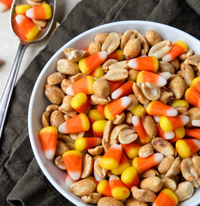 Candy Corn and peanuts mixed in a bowl with a few spilled to the side
