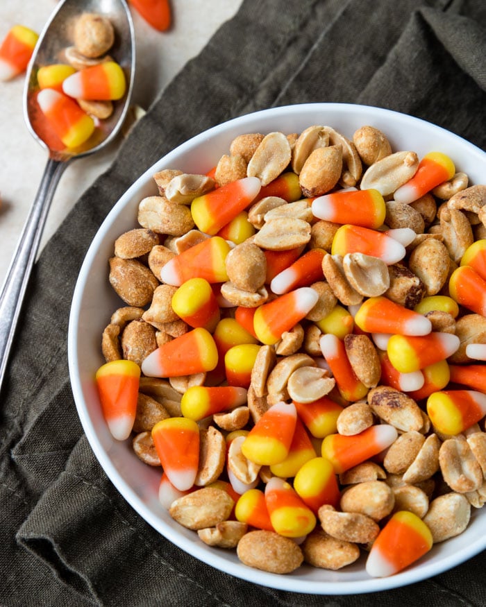 Candy Corn and peanuts mixed in a bowl with a few spilled to the side