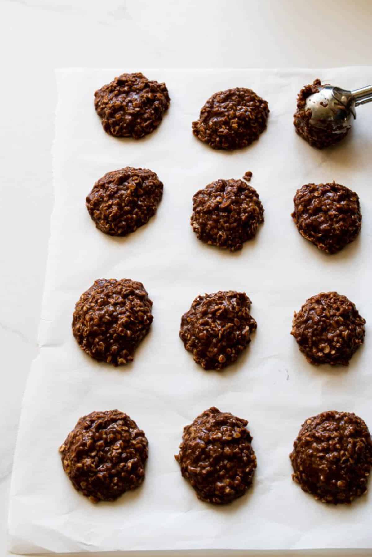Dropping no bake cookies on parchment paper with a scoop