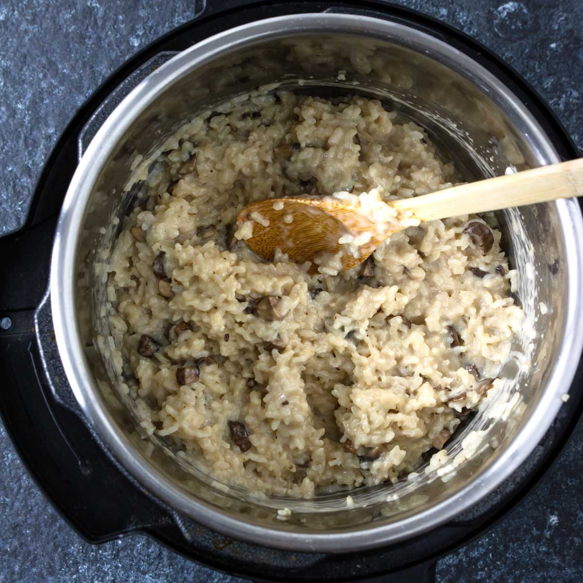 mushroom risotto in the instant pot with a wooden spoon