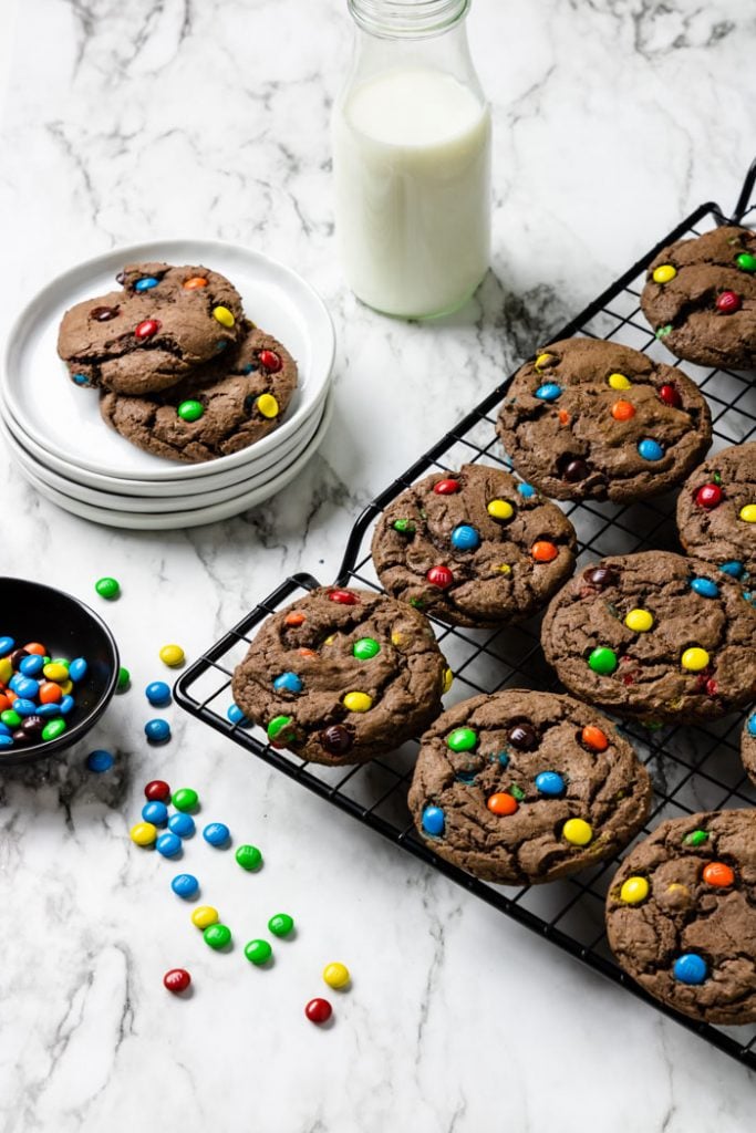 Chocolate Cake Mix Cookies on a cooling rack with milk and a plate of cookies