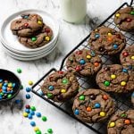 Chocolate cookies with M&M's on a cooling rack- pinterest text over top