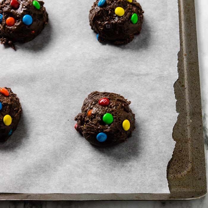 Cake Mix Cookie batter on a parchment lined baking sheet with M&M's pressed into the top