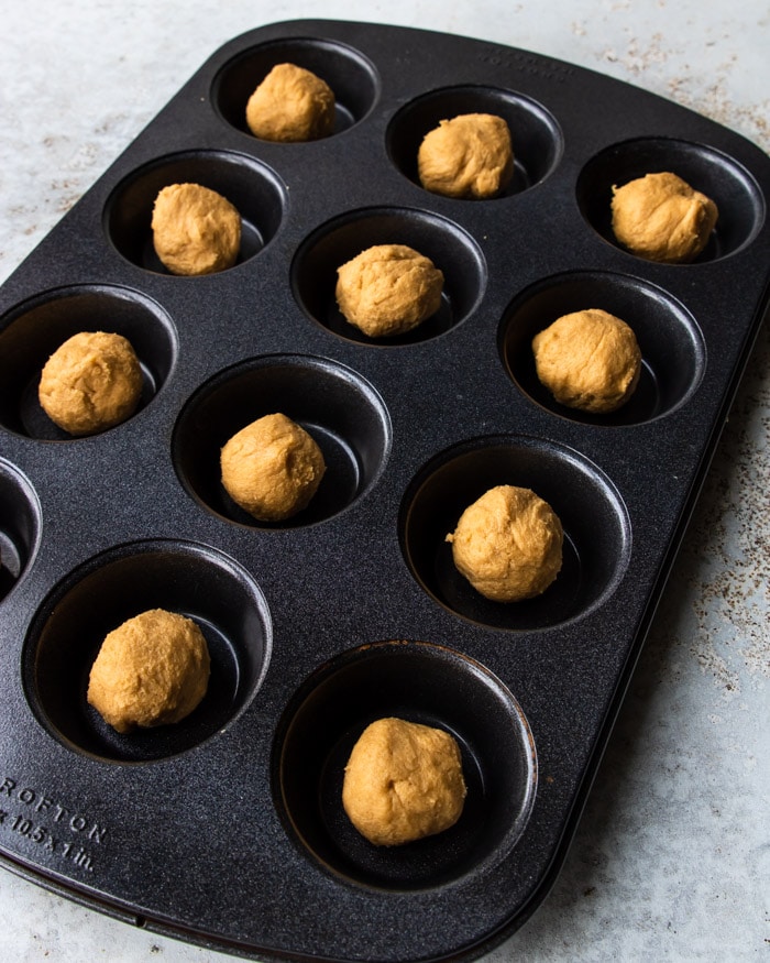 peanut butter cookie dough in a muffin tin, ready to bake for Reese's Peanut Butter Cup Cookies