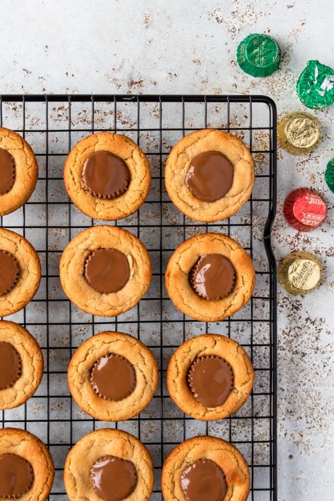 Peanut Butter Cup Cookies on a cooling rack with Reese's Peanut Butter Cups to the side