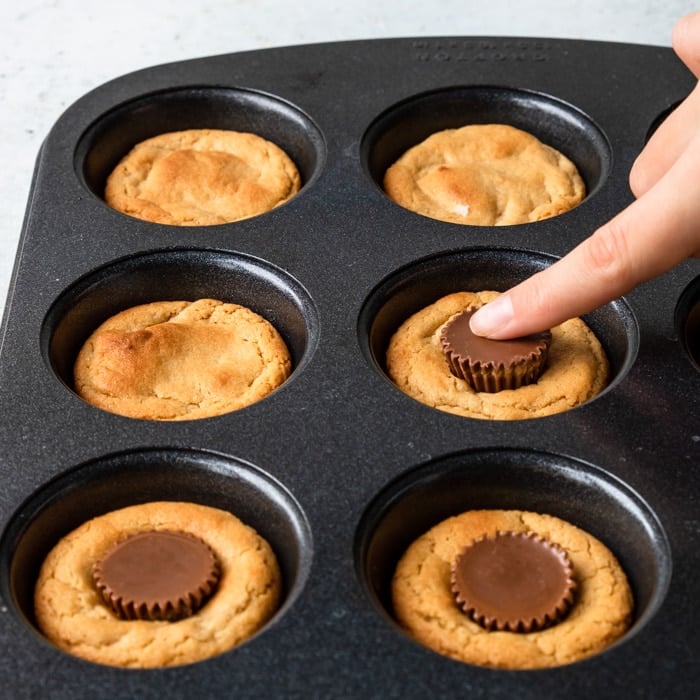 pressing an Reese's peanut butter cup in the warm cookie