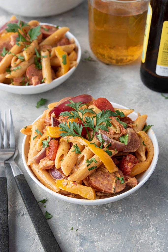 two bowls of creamy cajun pasta with peppers and sausage