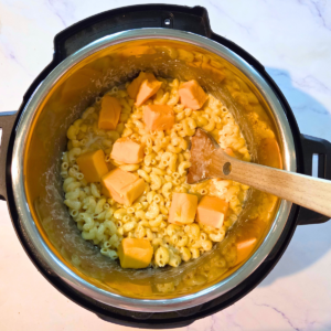 cubes of Velveeta in an Instant pot of cooked macaroni