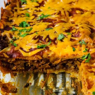 beef enchilada Casserole with a slice cut out so you can see the layers of corn tortillas, beef, cheese and sauce