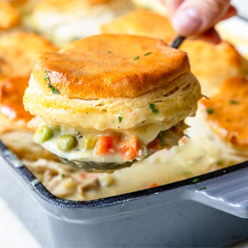 A ladle serving chicken and biscuits