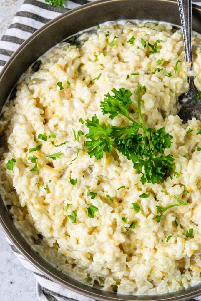 cheesy rice in a grey bowl topped with parsley
