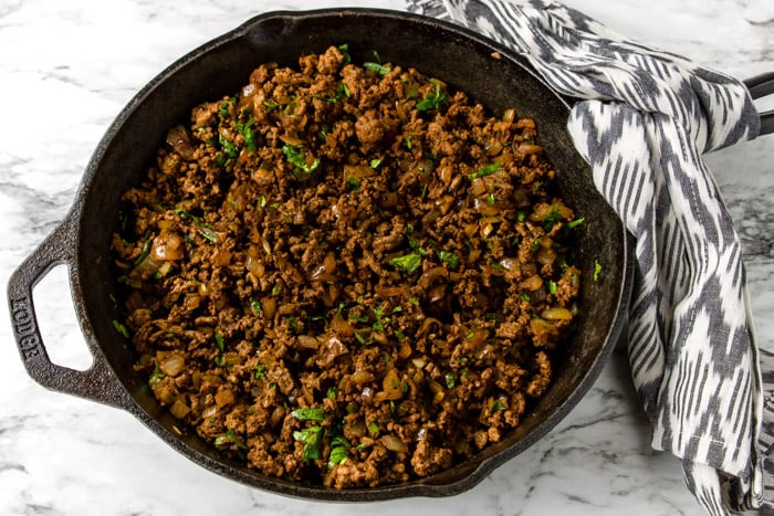 ground beef in a skillet with onions, garlic and cilantro
