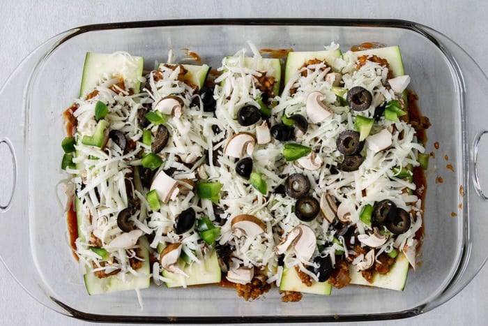 zucchini boats filled with Italian sausage and topped with mushrooms, peppers, black olives, and cheese