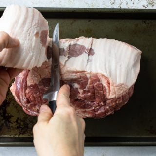 Cutting the fat cap from the pork roast with a knife